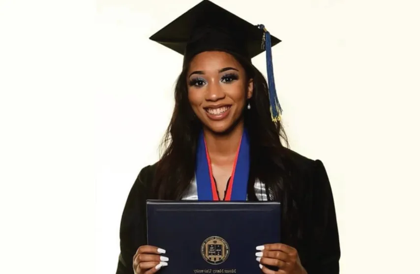 A smiling women holding a diploma from Mount Mercy University.