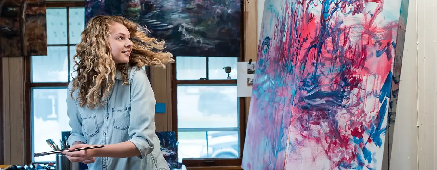 A female artist painting on a canvas in an art studio.