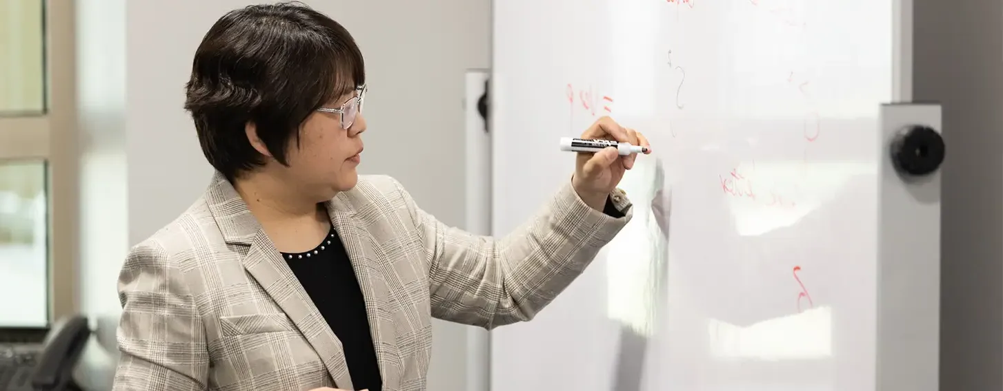 A woman writing on a whiteboard, illustrating her ideas and thoughts.